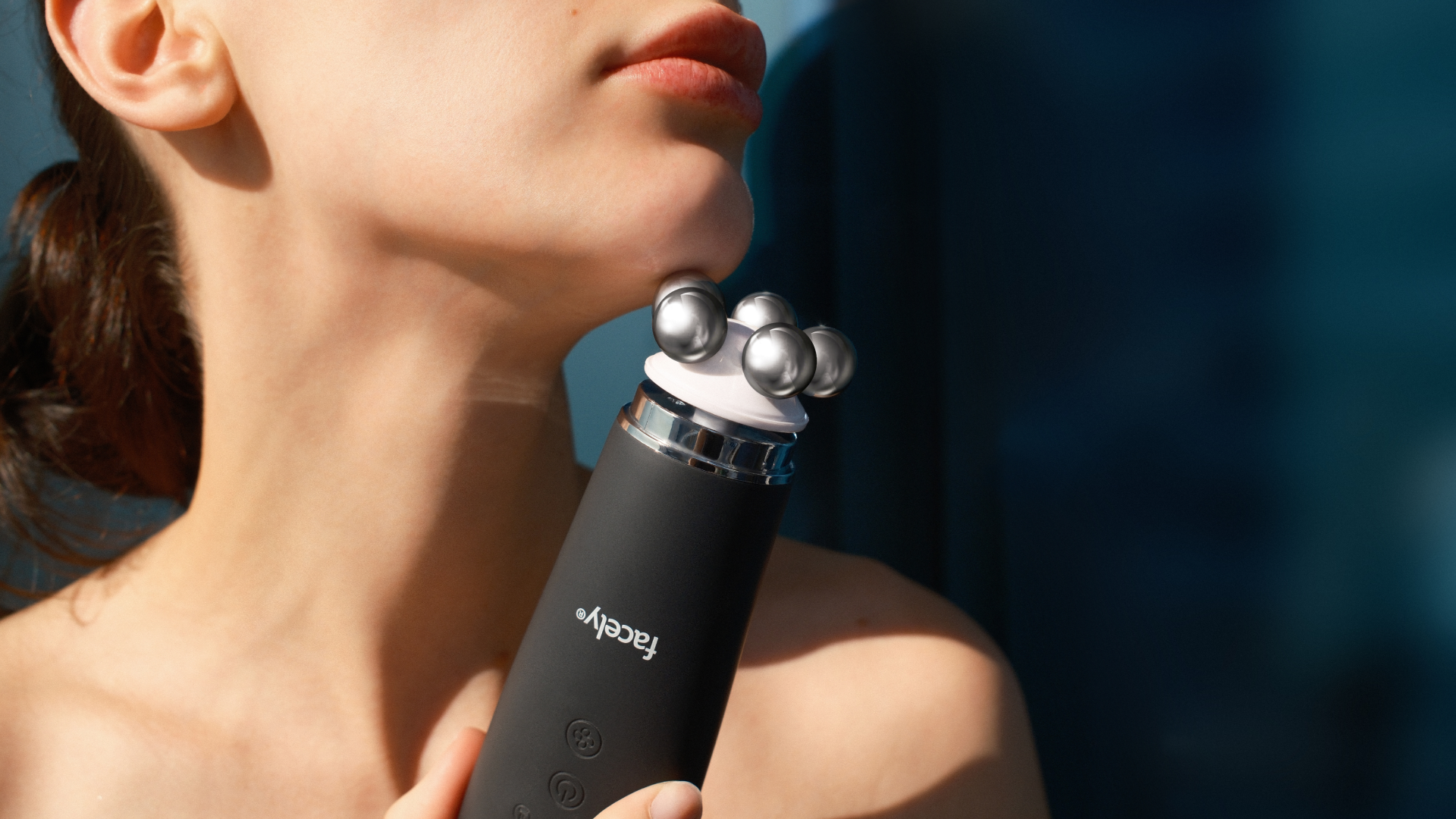 Person using a black handheld device on their neck with a blurred blue background